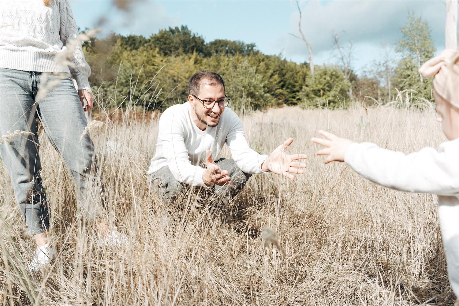 Familienfotograf Duisburg: Vater fängt sein lachendes Kind auf einem Feld auf
